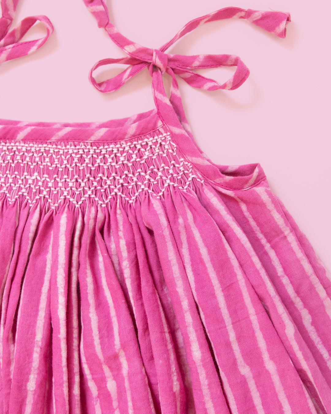 Close-up of hand-smocked yoke on taffy pink striped baby dress in soft breathable Jaipur cotton perfect for girl baby