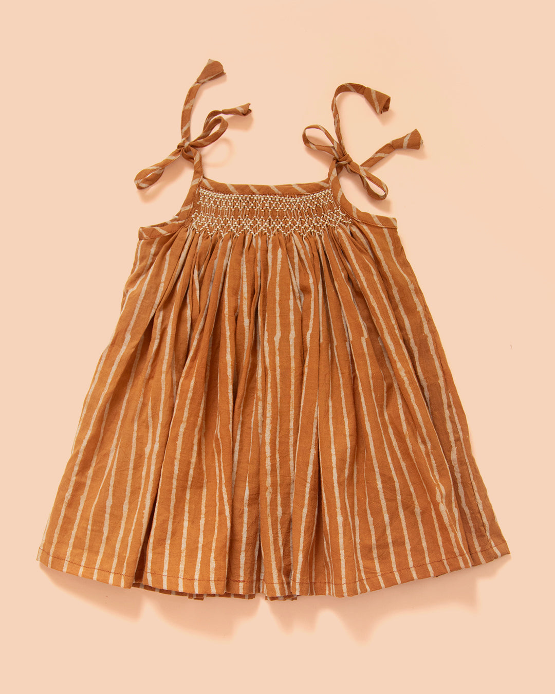 Hand-smocked Jaipur cotton baby dress in terracotta stripe with tie-up shoulders for newborn girls by MyBud