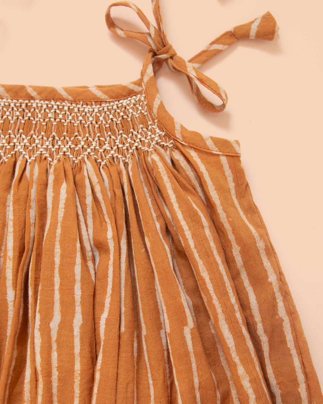 Close-up of hand-smocked yoke on Sienna baby dress in soft Jaipur cotton with earthy terracotta stripes